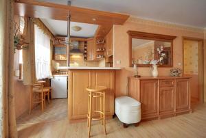 a kitchen with wooden cabinets and a bar with a stool at Apart-Invest apartament Fabiański in Szklarska Poręba