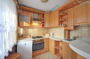 a kitchen with wooden cabinets and a stove top oven at Apart-Invest apartament Fabiański in Szklarska Poręba