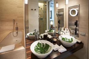 a bathroom with three sinks and a tub at Sina The Gray in Milan