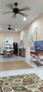 een woonkamer met een plafondventilator en een tafel bij HOMESTAY AQILAH PASIR PUTEH KELANTAN in Pasir Puteh