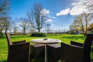 eine Terrasse mit einem Tisch, 2 Stühlen und einem Feld in der Unterkunft Parkhotel De Wiemsel in Ootmarsum