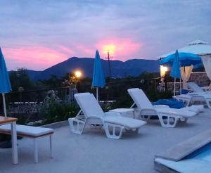 a group of lounge chairs and umbrellas on a patio at Luštica Apartments in Luštica