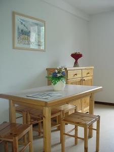 a wooden table with chairs and a vase of flowers on it at La résidence du Pleynet aux 7 Laux in La Ferrière