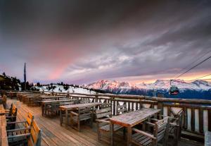 a group of tables and benches on a deck with mountains at Hamilton Lodge & Spa in Belalp