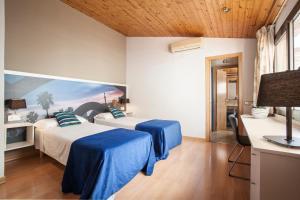 a room with two beds and a desk with a television at BCNGOTIC 50 in Barcelona