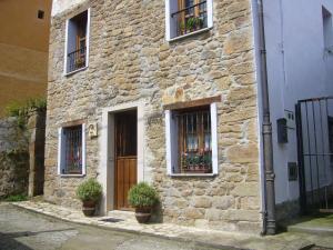 a stone building with two windows and a door with potted plants at Casa Encarnacion in Santo Emiliano