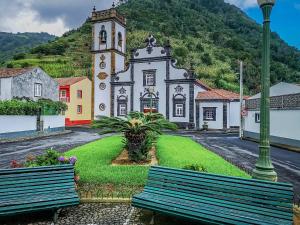 une église avec deux bancs devant un bâtiment dans l'établissement Casa do vermelho, à Povoação