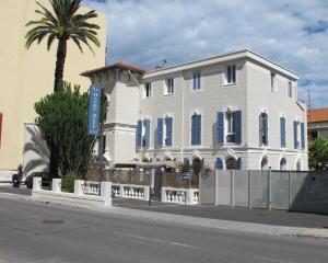 ein weißes Haus mit einer Palme davor in der Unterkunft Hotel Le Havre Bleu in Beaulieu-sur-Mer