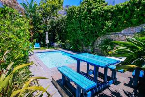 una mesa de picnic azul y un banco junto a una piscina en Cape Paradise Lodge and Apartments, en Ciudad del Cabo