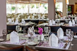 a dining room with tables with glasses and napkins at Porto Platanias Village Resort in Plataniás