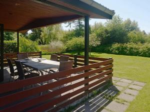 a wooden fence with a table and chairs under a pavilion at 6 person holiday home in Pr st in Togeholt