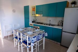 ドンナルカータにあるVacanze Plaja Grandeのキッチン(青いキャビネット、テーブル、椅子付)