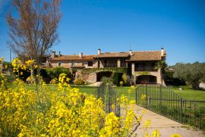 a house with a fence and a field of yellow flowers at Mas Vermell in Fontanilles