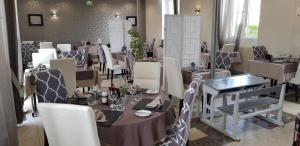 Logis Hotel Restaurant Le Vedaquais في Vaas: غرفة طعام مع طاولات وكراسي بيضاء