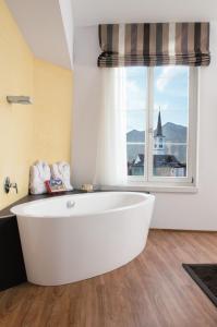 a white bath tub in a bathroom with a window at Sorell Hotel Tamina in Bad Ragaz