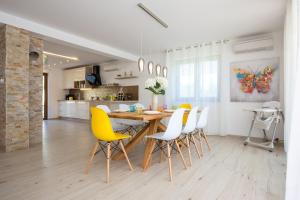 kuchnia i jadalnia z drewnianym stołem i żółtymi krzesłami w obiekcie Villa Sara - perfect family holiday w Krku