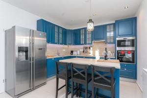 eine Küche mit blauen Schränken und einem Kühlschrank aus Edelstahl in der Unterkunft Villa Fortunei in Mokošica