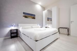a white bedroom with a white bed and a mirror at Dimora Santo Stefano: Ampia, con Giardino privato in Bologna