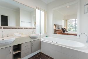 a white bathroom with two sinks and a large mirror at Cosy Corner by the BnB Collection in Albany