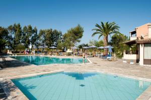 a large swimming pool with chairs and umbrellas at a resort at Helena Apartments & Villas in Sidari
