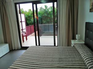 a bedroom with a bed and a sliding glass door at Aparthotel El Faro in Cullera