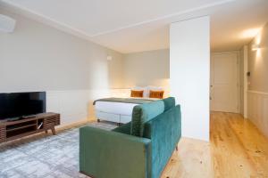 uma sala de estar com uma cama, um sofá e uma televisão em Barão Oporto Apartments no Porto