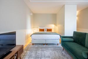 a bedroom with a bed and a couch and a tv at Barão Oporto Apartments in Porto