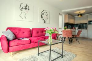 sala de estar con sofá rojo y mesa en W&K Apartments White&Grey, en Koszalin