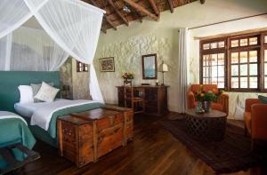 ein Schlafzimmer mit einem Bett, einem Tisch und einem Spiegel in der Unterkunft Rivertrees Country Inn in Usa River + 80 Fotos