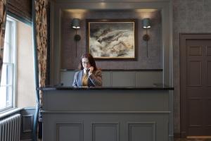 馬里卡爾特的住宿－瑪麗卡特之家酒店，一名妇女在柜台后面用手机说话