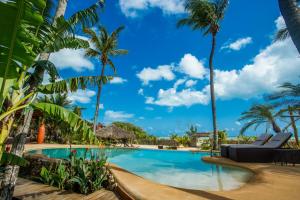 a pool at a resort with palm trees at Hara Pousada e SPA in São Miguel do Gostoso