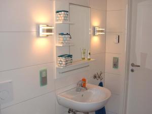 a bathroom with a sink and a mirror and lights at Ferienwohnungen "allerleigrün" in Langenroda