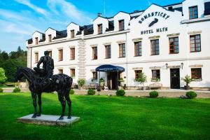 Una statua di un uomo su un cavallo di fronte a un edificio di Romantic Hotel Mlýn Karlstejn a Karlštejn