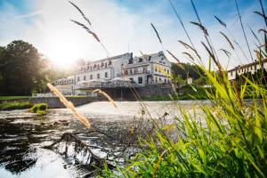 un grande edificio bianco in mezzo a un fiume di Romantic Hotel Mlýn Karlstejn a Karlštejn