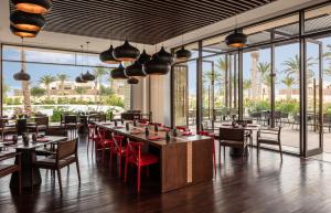 Anantara Sahara-Tozeur Resort & Villas في توزر: مطعم بطاولات وكراسي ونوافذ كبيرة