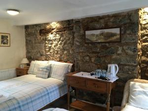 Aber Cottage B&B في دولغيلوو: غرفة نوم بسريرين وجدار حجري