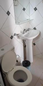 a white bathroom with a toilet and a sink at Las Piedras del Paso in Paso de la Patria