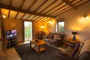 a living room with a couch and a tv at Sebright Cottage, Borrowby Farm Cottages in Staithes