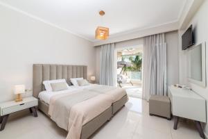 a white bedroom with a large bed and a television at Mamfredas Luxury Resort in Tsilivi