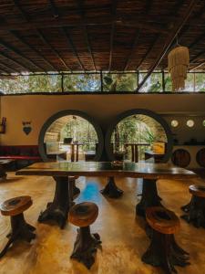 una mesa grande y taburetes en una habitación con ventanas en Hostal Mulut Tulum, en Tulum