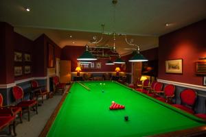 a pool table in a billiard room with red chairs at Petwood Hotel in Woodhall Spa