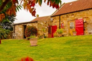 een stenen huis met rode deuren en een tuin bij Rosecombe, Borrowby Farm Cottages in Staithes