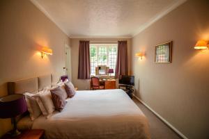 a bedroom with a large bed and a desk at Petwood Hotel in Woodhall Spa