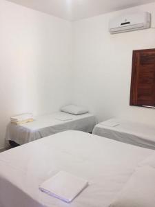 a room with two beds and a white wall at Batista's Beach in Luis Correia