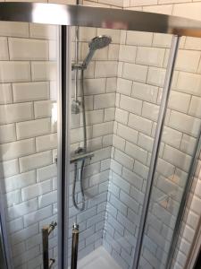 a shower in a bathroom with white tiles at 3. Stylish Private Double Room Near Manchester City Centre in Manchester
