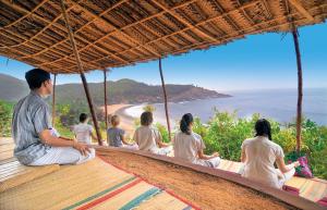 a group of people sitting on a bench looking at the beach at SwaSwara Gokarna - a CGH Earth Experience in Gokarna
