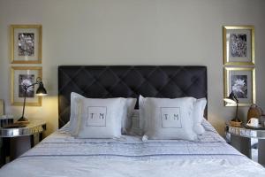 a bed with white pillows and a black headboard at Torri E Merli Boutique Hotel in Lákka
