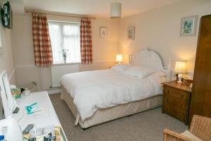 a bedroom with a white bed and a window at The Garden House Grittleton in Grittleton