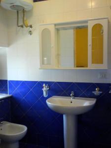 een blauwe en witte badkamer met een wastafel en een spiegel bij Casa Anita in Siracusa
