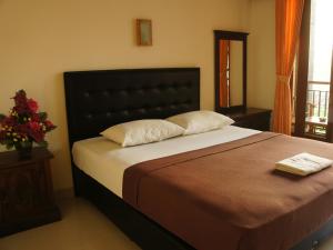 um quarto com uma cama grande e uma cabeceira preta em Waringin Homestay em Kuta